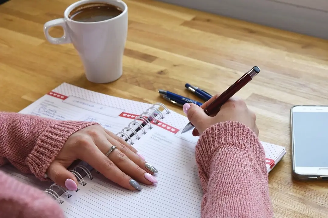 Writing in a planner with a cup of coffee